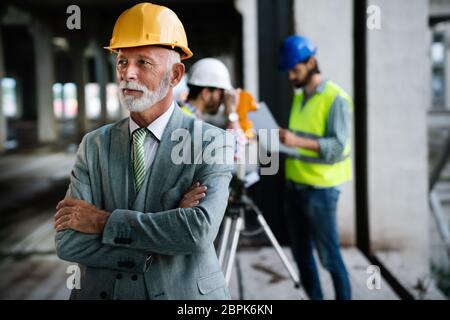 Two satisfied engineers talking at building site with construction structure in background Stock Photo