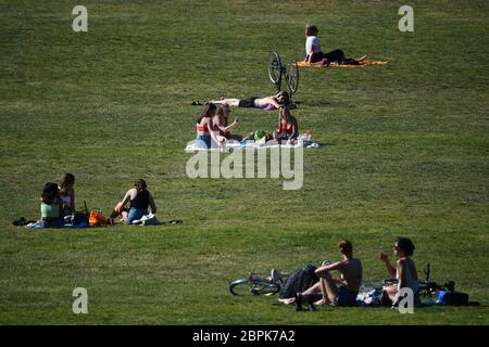 People sit on the grass and enjoy the hot weather in Greenwich Park, London, after the introduction of measures to bring the country out of lockdown. Stock Photo
