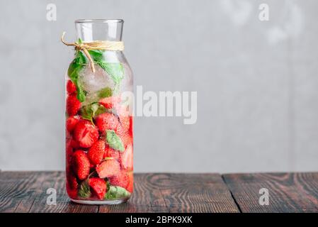 Bottle of Infused Water with Fresh Strawberry and Basil Leaves. Copy Space. Stock Photo