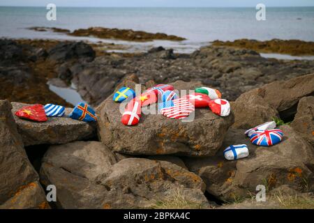The stones painted with national  flags: Norway, Finland, USA, China,Iceland, Switzerland, Sweden, Greece, Denmark on shore of Iceland.