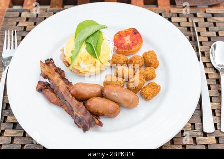 Delicious breakfast with eggs Benedict, bacon, sausage, and potato hash brown Stock Photo