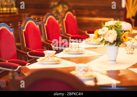 Dining room of medieval castle in Belarus. Old beatiful red chairs and table with flowers Stock Photo