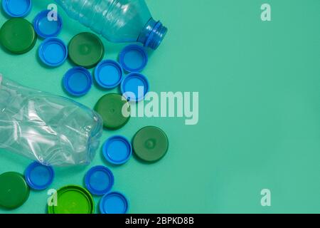 Top view of plastic bottlle caps nad plastic bottles on green background with copy space Stock Photo