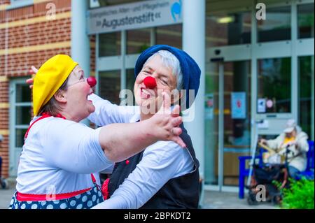 Schwerin, Germany. 19th May, 2020. Kerstin Daum as 'Kiki' (l) and Ines Vowinkel as 'Fine' make music as clinic clowns in front of the 'Augustenstift' nursing home which is closed to visitors. Due to corona protection measures, the two clowns are only allowed to play in front of balconies and on terraces in front of the house. Credit: Jens Büttner/dpa-Zentralbild/ZB/dpa/Alamy Live News Stock Photo