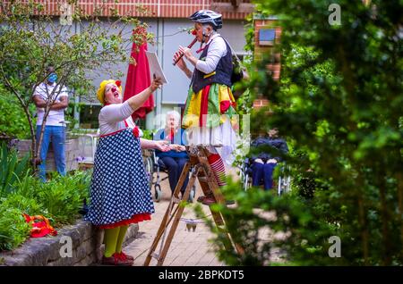 Schwerin, Germany. 19th May, 2020. Kerstin Daum as 'Kiki' and Ines Vowinkel (r) as 'Fine' make music as clinic clowns in front of the 'Augustenstift' nursing home which is closed to visitors. Due to corona protection measures, the two clowns are only allowed to play in front of balconies and on terraces in front of the house. Credit: Jens Büttner/dpa-Zentralbild/ZB/dpa/Alamy Live News Stock Photo