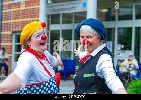 Schwerin, Germany. 19th May, 2020. Kerstin Daum as 'Kiki' (l) and Ines Vowinkel as 'Fine' make music as clinic clowns in front of the 'Augustenstift' nursing home which is closed to visitors. Due to corona protection measures, the two clowns are only allowed to play in front of balconies and on terraces in front of the house. Credit: Jens Büttner/dpa-Zentralbild/dpa/Alamy Live News Stock Photo
