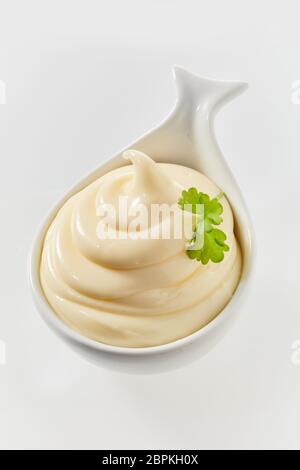 Twirled freshly made mayonnaise in a ceramic spoon to be served as an accompaniment to a formal meal high angle on white Stock Photo