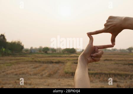 Hands making frame with sunset. Close up of woman hands making frame gesture. Stock Photo