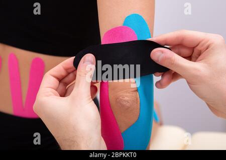 Close-up Of Physiotherapist Applying Kinesiology Tape On Patient's Elbow Stock Photo