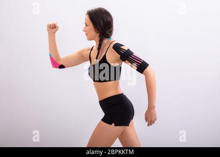 Side View Of A Young Woman Running With Physio Tape On Her Body Stock Photo