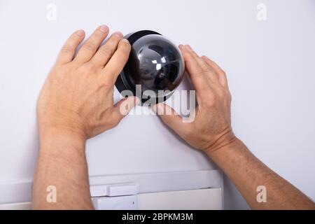 Close-up Of Male Technician Hand Installing Surveillance Camera On Wall Stock Photo