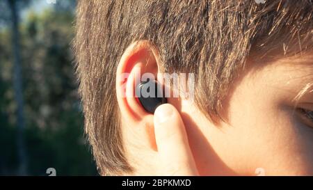Black compact headphones in person's ear close up Stock Photo