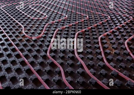 Underfloor heating system installation. Close up on water floor heating system interior of a new residential building. Pipes filled with propylene Stock Photo