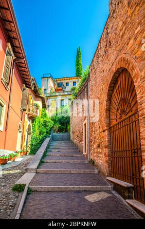 Staircase stairway of narrow street between stone walls. Scalinata Castel S. Pietro leading to Castel San Pietro in Verona city historical centre, blue sky background, Veneto Region, Northern Italy Stock Photo
