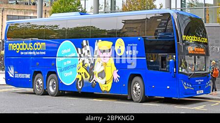 Front & side view of Megabus.com low cost intercity bus travel at bus stop in Newcastle advertising for its links with Silverstone circuit England UK Stock Photo