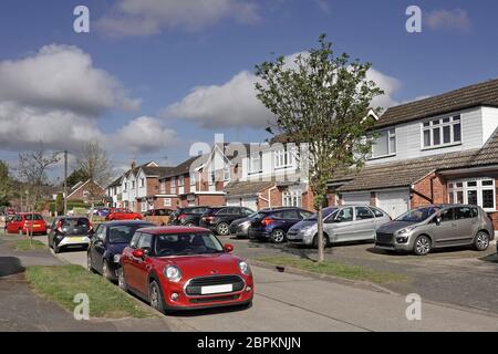 Residential suburb street car parking scene in road & houses with cars on original lawn front garden now paved vehicle park space  Essex England UK Stock Photo