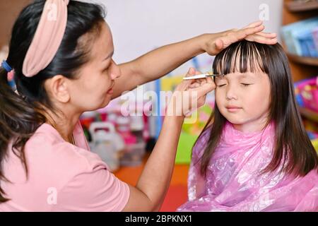 Asian Mother cutting hair to her daughter at home while stay at home safe from Covid-19 Coronavirus during lockdown city. Self-quarantine and social