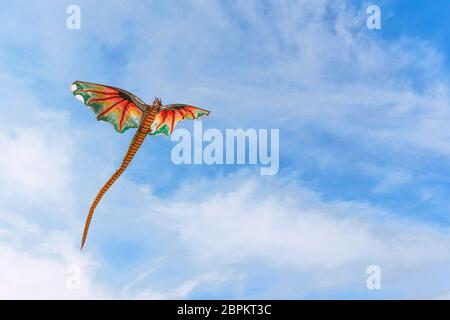 A red chinese kite with dragon head flying in the wind, Bali, Indonesia, april 21, 2018 Stock Photo