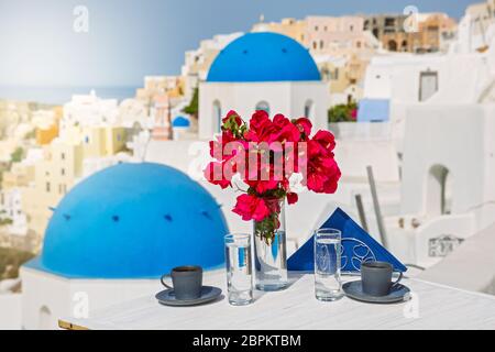 Drinks and flowers on the table with a view of the landscape of the island of Santorini Stock Photo