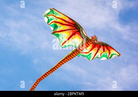 Indonesian kite with an ugly dragon head and a long tail flying in the wind, Sanur, Bali, Indonesia, April 21, 2018 Stock Photo