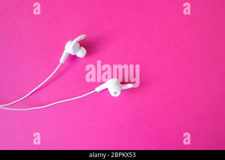 White headphones with a wire on a pinkbackground. The concept of gadgets. Stock Photo
