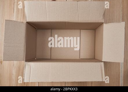 open empty rectangular box of brown cardboard on a wooden background, top view Stock Photo