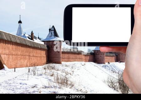 travel concept - tourist photographs of walls of Monastery of Our Savior and St Euthymius in Suzdal town in winter of Russia on smartphone with cutout Stock Photo