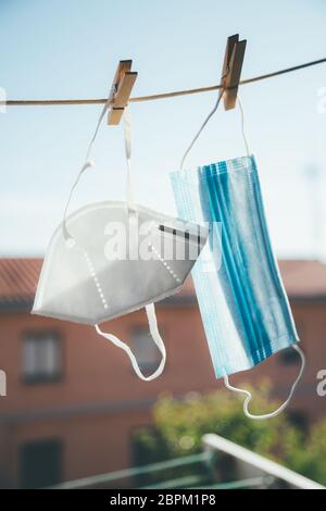 Two facial protective masks of different types hanging in the sun to disinfect Stock Photo