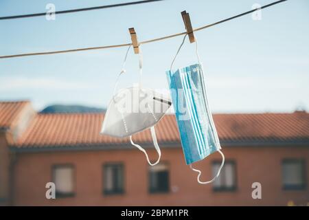 Two facial protective masks of different types hanging in the sun to disinfect Stock Photo