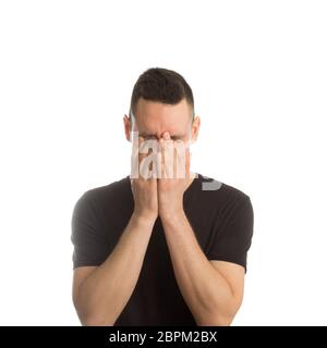 Man in t-shirt covering his face with hands o Stock Photo