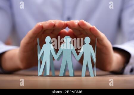 Close-up Of A Person's Hand Protecting Human Figures Forming Circle Stock Photo