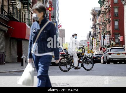 New York, United States. 19th May, 2020. A man wears a protective suit and face mask while riding a bicycle on Mott street in the Chinatown section of Manhattan during the COVID-19 Pandemic in New York City on Tuesday, May 19, 2020. The U.S. Coronavirus death toll now tops 90,000 and the number of reported cases reaches 1.5 million. Photo by John Angelillo/UPI Credit: UPI/Alamy Live News Stock Photo