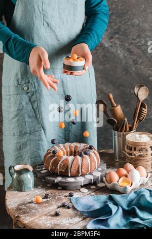 Female hands pouring berries on easter Yeast cake on wooden plate Stock Photo
