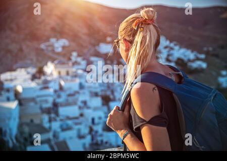 Traveler girl enjoying mountainous village view in bright sun light, many nice little white houses built on the mountain cliff, interesting summer adv Stock Photo