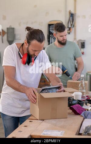 two men in workwear in a carpenter's workshop with parcel Stock Photo