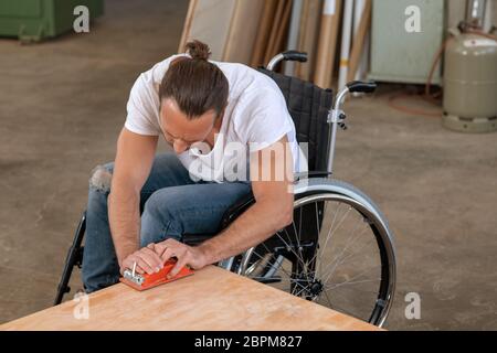 disabled worker in wheelchair in a carpenter's workshop Stock Photo