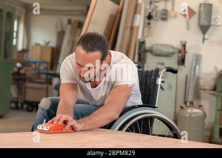 disabled worker in wheelchair in a carpenter's workshop Stock Photo