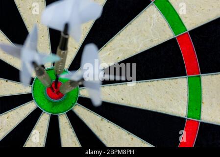 three darts thrown at the bulls eye of a dartboard Stock Photo