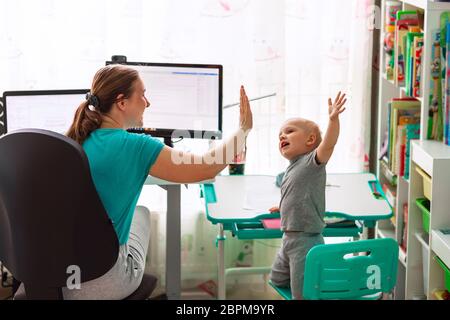 Mother with kid trying to work from home during quarantine. Stay at home, work from home concept during coronavirus pandemic Stock Photo