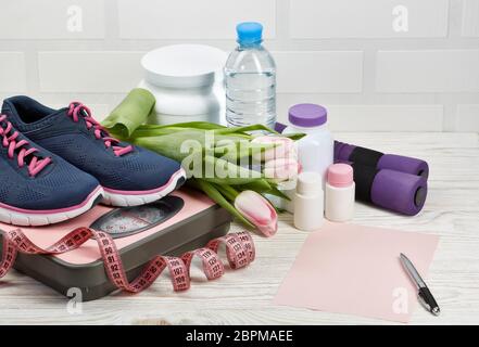 Female fitness still life with copy space.  Sports  nutrition (supplements), sport accessories and dumbbells isolated on a white background. Healthy l Stock Photo