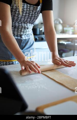 Anonymous person using a rolling pin to make fresh pasta at home. Stock Photo