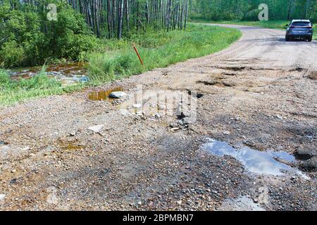 A washed out gravel road with a vehicle in the background. Stock Photo