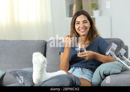 Disabled woman satisfied with painkiller pill sitting on a couch in the living room at home Stock Photo