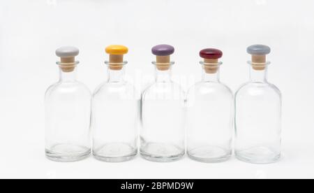 small glass bottles with the colored cap lined up on a white surface Stock Photo