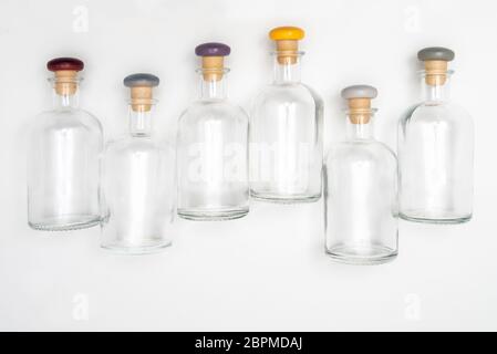 small glass bottles with the colored cap lined up on a white surface Stock Photo