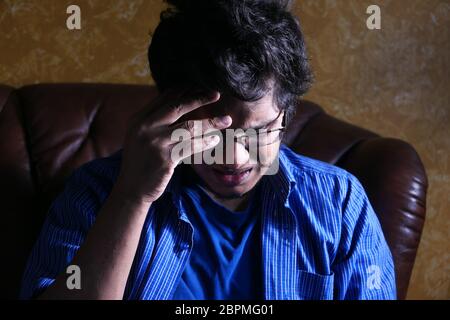 A sick man with suffering headache sitting on sofa  Stock Photo