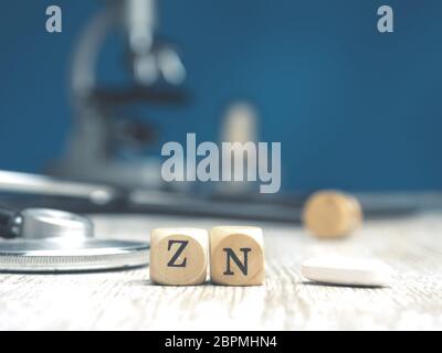 The periodic word zinc on small wooden blocks with a stethoscope on a table, health care or medical concept with space for text Stock Photo