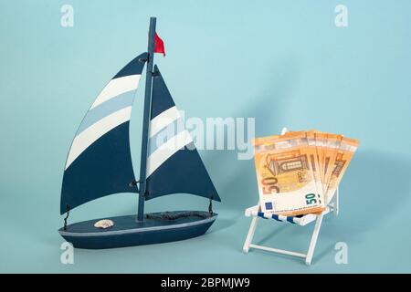Summer Vacation Concept with toy boat with fifty Euro Banknotes on blue background Stock Photo
