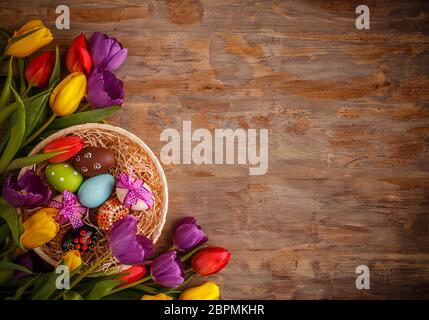 Easter eggs and tulips on old wooden background. View from above with copy space Stock Photo