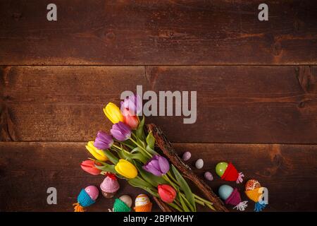 Easter composition with tulips and Easter eggs with little hats on wooden planks Stock Photo